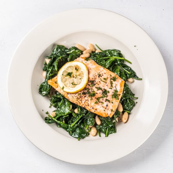 Hampton Junction's salmon with spinach, white beans, and a lemon slice on a white plate.