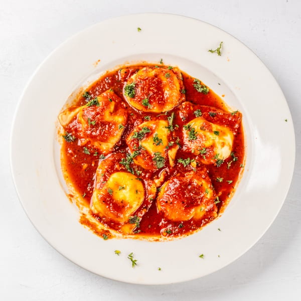 Hampton Junction's ravioli, topped with rich red sauce and fresh parsley, served on a white plate.
